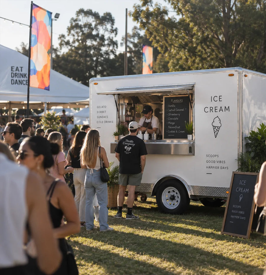 Custom white mobile ice cream trailer serving gelato and desserts to customers at an outdoor festival